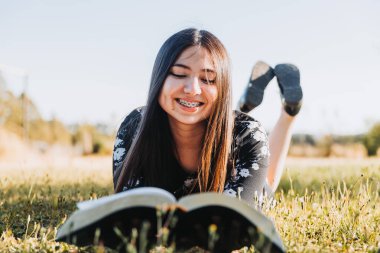Close up of a young woman lying while reading the bible on the grass with a blurred background. High quality photo