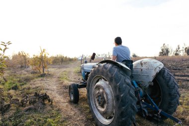 Gün batımında çiftliğinin ortasında eski bir traktörü süren Latin bir çiftçinin arka ışıklandırması. Tarım sürdürülebilirliği. Uzayı kopyala Yatay olarak. Yüksek kalite fotoğraf