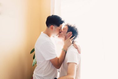 two gay men wearing white t shirts, kissing each other on the mouth. LGBT relationship. High quality photo