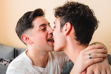 two gay men wearing white t shirts, kissing each other on the mouth. LGBT relationship. High quality photo