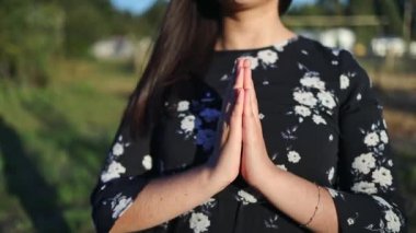 Unrecognizable believer woman with praying hands at sunset in the field. Communion with God. High quality FullHD footage