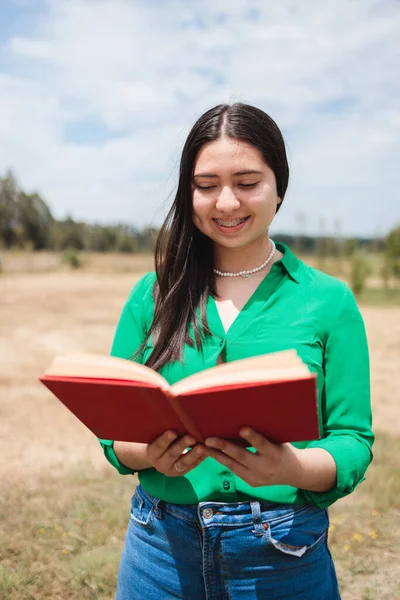 Smiling old fashioned young woman reading a book in the greenery of the field. High quality photo