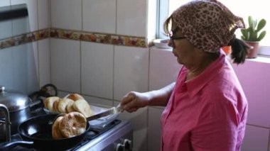 Traditional indigenous latin elderly woman cooking sopaipillas, traditional chilean fried food. High quality 4k footage