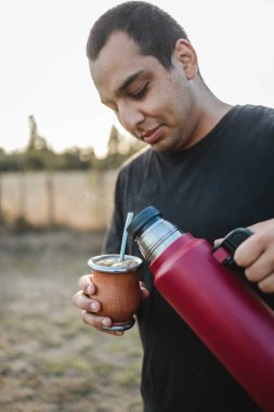 Gün batımında kırsalda genç bir adam Yemba 'yı tutuyor. Uzayı kopyala Yüksek kalite fotoğraf