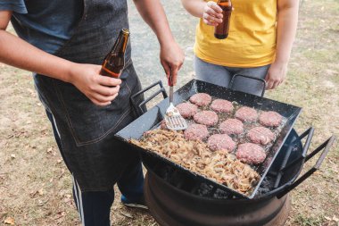 Mangal ızgarasında hamburger ve soğan hazırlayan tanınmamış Latin genç adam. Yüksek kalite fotoğraf