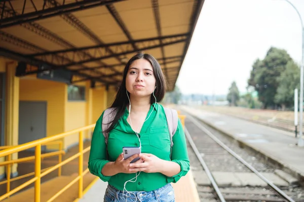 Urban Mobility and Connectivity: Young Girl Using Technology for Entertainment while Waiting for her Train. High quality photo