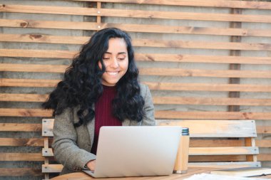Style 'da Uzaktan Çalışma: Laptop ve telefonlu bir Patio Cafe' de Genç, Esmer Latin Profesyonel. Yüksek kalite fotoğraf