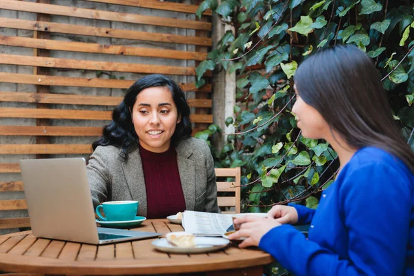 Financial Security Conversation: Young Latina Woman Selling Life Insurance to Another Woman at a Cozy Cafe. High quality photo