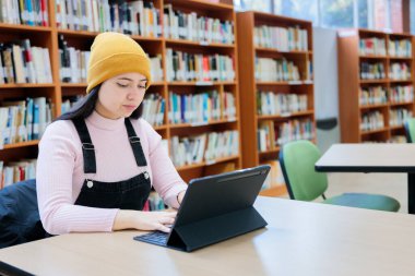 Akademik Takipler: Genç Bayan Üniversite Öğrencisi Kütüphanede Tabletle Öğreniyor. Yüksek kalite fotoğraf