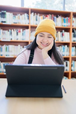 Akademik Takipler: Genç Bayan Üniversite Öğrencisi Kütüphanede Tabletle Öğreniyor. Yüksek kalite fotoğraf