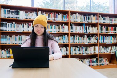 Akademik Takipler: Genç Bayan Üniversite Öğrencisi Kütüphanede Tabletle Öğreniyor. Yüksek kalite fotoğraf