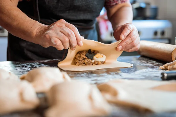 Latin Elderly Woman Making Chilean Baked Empanadas in the Authentic Ambience of her Countryside Home Kitchen. Close up. High quality photo