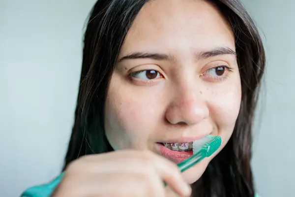 Close up of young woman with braces brushing her teeth in the bathroom. Oral Hygiene routine. High quality photo