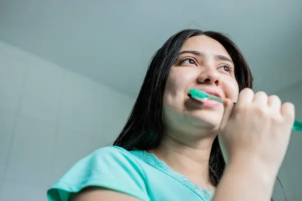 Close up of young woman with braces brushing her teeth in the bathroom. Oral Hygiene routine. High quality photo