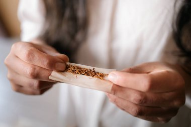 El ile sarılıp sigara içen tanınmamış bir kadın var. Kusursuz bir el işi. O, beyaz bir bluz giyiyor. Yüksek kalite fotoğraf