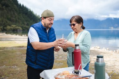 Patagonya Sükuneti: Latin Orta Çağ Evliliği Dağ Gölü kıyısında Yerba Mate ile Doğa ve Kahvaltıda Keyif Almaktadır. Yüksek kalite fotoğraf