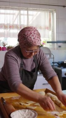 Kıdemli Latin kadın hamur yoğuruyor, ev mutfağında Şili usulü kızarmış hamur işi Calzones rotoları pişiriyor. - Evet. dikey 4k görüntü