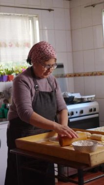 Geleneksel Latin orta yaşlı kadın mütevazı evcil mutfağında yemek pişiriyor ve yemek hazırlıyor. dikey 4k görüntü