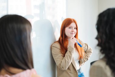 Genç bir kadın yönetici, toplantı odasındaki iş arkadaşlarına karşı takım stratejisi oluşturmak için beyaz tahtayı kullanıyor. Yüksek kalite fotoğraf
