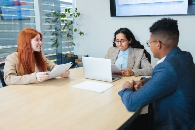 Genç profesyonellerden oluşan bir ekip, modern bir ofiste veya toplantı odasında aktif olarak iş görüşmelerine katılıyor.