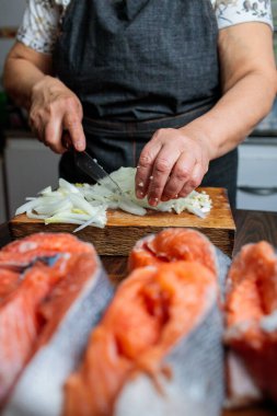 Ev mutfağında somon sosu yapmak için soğan ve sarımsak dilimleyen tanınmamış son sınıf öğrencisi bir kadın. Yüksek kaliteli resim