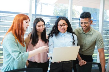 Multiethnic team of young professionals collaborating on business strategies, standing around a table and brainstorming in a modern office clipart