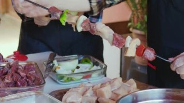 Beyaz bir masada tavuk ve sığır eti pişirirken soğan ve biber doğrayan tanınmayan yaşlı çift.