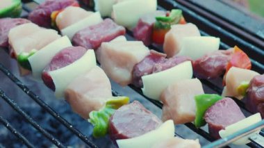 Çiğ et ve tavuk şişleri ızgarada ızgara yapıyor, yanında da et ve tavuk parçaları.