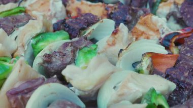 Çiğ et ve tavuk şişleri ızgarada ızgara yapıyor, yanında da et ve tavuk parçaları.