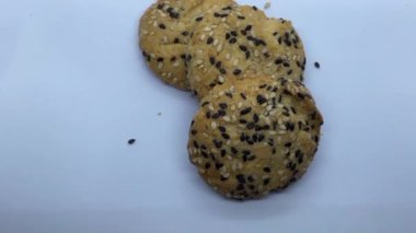 Susam tohumları serpiştirilmiş bisküviler beyaz arka planda yuvarlaktır. 