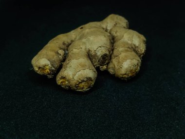 ginger root (Zingiber officinale) or ginger, is widely used as a spice and a folk medicine, on black background  clipart