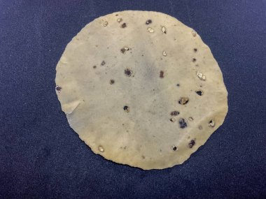 Çiğ, ince, mercimek unundan yapılmış ve karabiberle tatlandırılmış papad. Hint atıştırmalıkları siyah arkaplan 