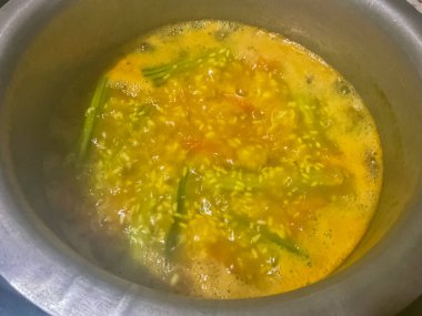 Khichdi ev mutfağında bir tencerede pişiriliyor. Tavuk budu sebze, domates, pirinç ve baharat.