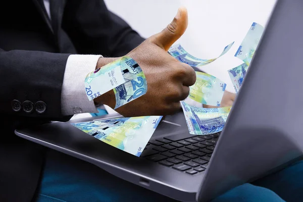 Kuwaiti dinar notes coming out of laptop with Business man giving thumbs up, Financial concept. Make money on the Internet, working with a laptop