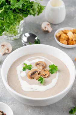 Kremalı mantar kremalı çorba, beyaz ahşap arka planda kızarmış ekmek ve otlar. Lezzetli konforlu yemek