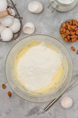 Adım adım tarif et. İtalyan cantucini kurabiyeleri yapma süreci. Çırpılmış yumurta, şeker, tereyağı, un ve kabartma tozu gri beton arka planda bir kasede. Üst görünüm