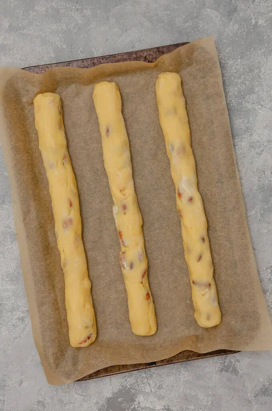 Recipe step by step. The process of making Italian cantucini cookies. Raw cookie dough on baking pan on a gray concrete background. Top view