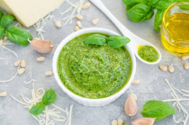 Geleneksel İtalyan fesleğen sosu beyaz bir kasede gri beton arka planda pişirmek için malzemelerle birlikte. Boşluğu kopyala