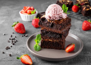 Fındıklı çikolatalı kek parçaları, koyu arkaplanda çilek ve dondurma. Seçici odak