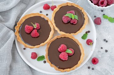 Gri zemin üzerinde ahududu olan lezzetli çikolatalı tart. Yaz tatlısı. Boşluğu kopyala.