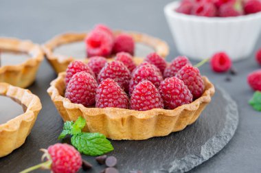 Çikolata kremalı lezzetli tart ve gri arka planda taze ahududu. Yaz tatlısı. Boşluğu kopyala