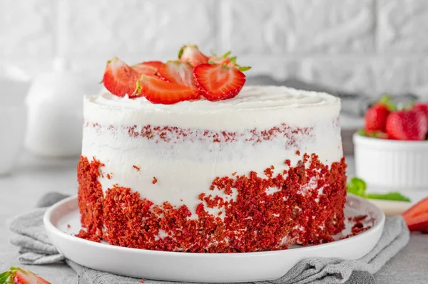 Red velvet cake with fresh strawberries. Festive layered cake from red sponge cakes and cream cheese frosting, American cuisine