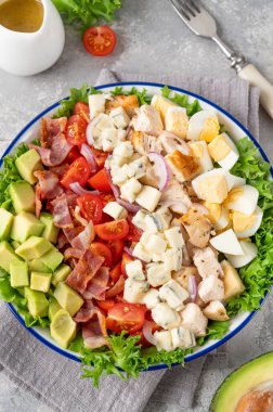 Geleneksel Cobb salatası kızarmış tavuk, avokado, taze domates, yumurta, pastırma ve peynirli bir tabak. seçici odak.