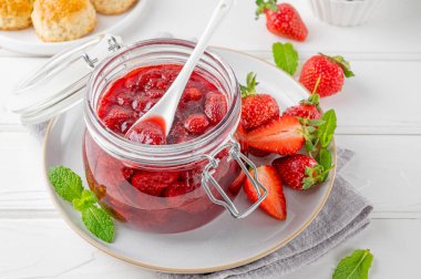 Cam kavanozda çilek reçeli ve beyaz ahşap bir masada taze böğürtlen. Yaz tatlısı. Boşluğu kopyala