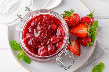 Cam kavanozda çilek reçeli ve beyaz ahşap bir masada taze böğürtlen. Yaz tatlısı. Boşluğu kopyala