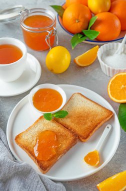 Turuncu marmelatlı tost mu yoksa gri arka planda bir fincan çay ile portakal reçeli mi? Nefis bir kahvaltı. Boşluğu kopyala