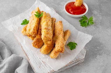 Gri bir arka planda domates sosuyla servis edilen haşlanmış sarımsaklı parmesan kabağı çubukları. Vejetaryen sağlıklı yemek. Seçici odak