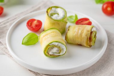 Beyaz ahşap zemin üzerinde krem peynirli, sarımsaklı ve otlu kabaklı mezeler. Seçici odak