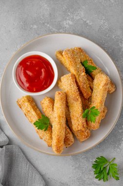 Gri bir arka planda domates sosuyla servis edilen haşlanmış sarımsaklı parmesan kabağı çubukları. Vejetaryen sağlıklı yemek. Seçici odak