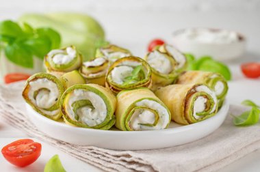 Beyaz ahşap zemin üzerinde krem peynirli, sarımsaklı ve otlu kabaklı mezeler. Seçici odak